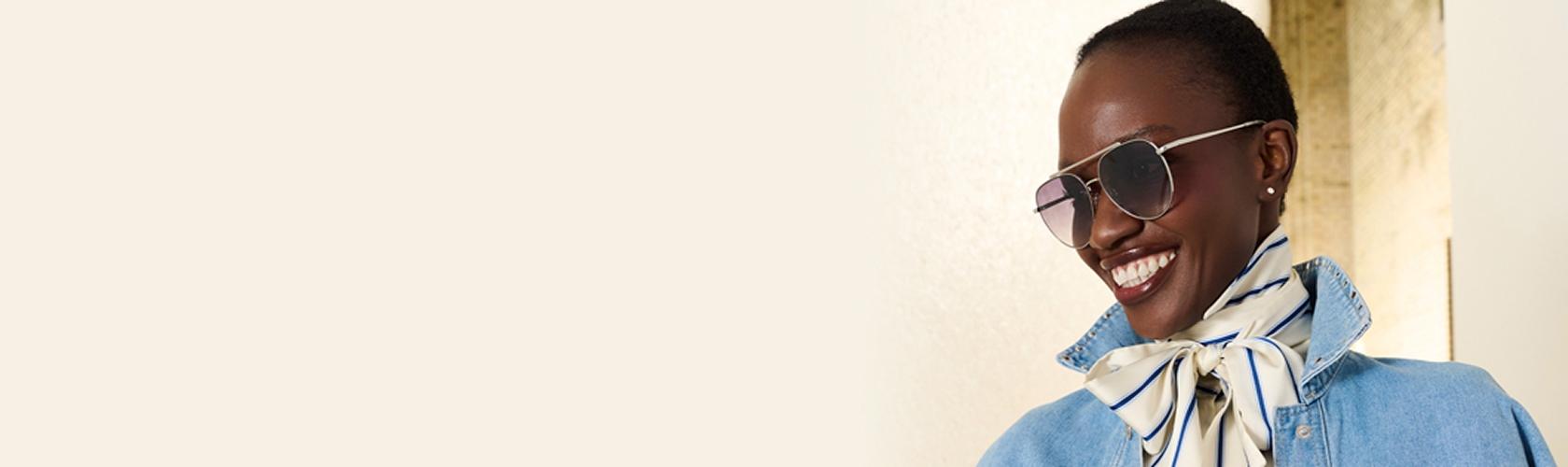 Woman wearing sunglasses and a denim outfit styled for a store opening at a vibrant shopping centre